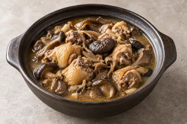 AI illustration: Bone-in chicken simmered with abundant whole brown mushrooms in a rustic dark clay pot.