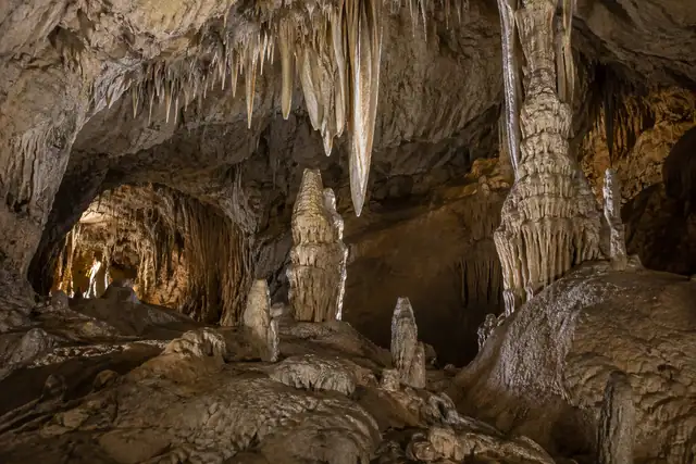 AI illustration: A detailed medium view of plausible cream and grey limestone cave formations: a few stalagmites.