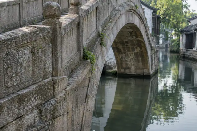 AI illustration: A close side view of a modest old Chinese stone pedestrian bridge: weathered stone parapet blocks.