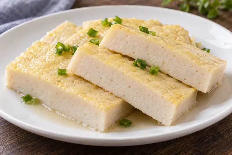 AI illustration: Neat slices of a pale steamed fish-paste cake.