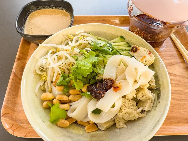 Wide noodle sheets with sesame sauce and accompaniments; a representative sesame-liangpi presentation.