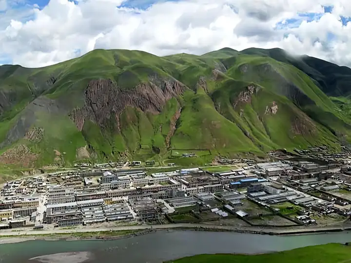 Baqên County (巴青县) — representative view · 陡峭绿山脚下的城镇