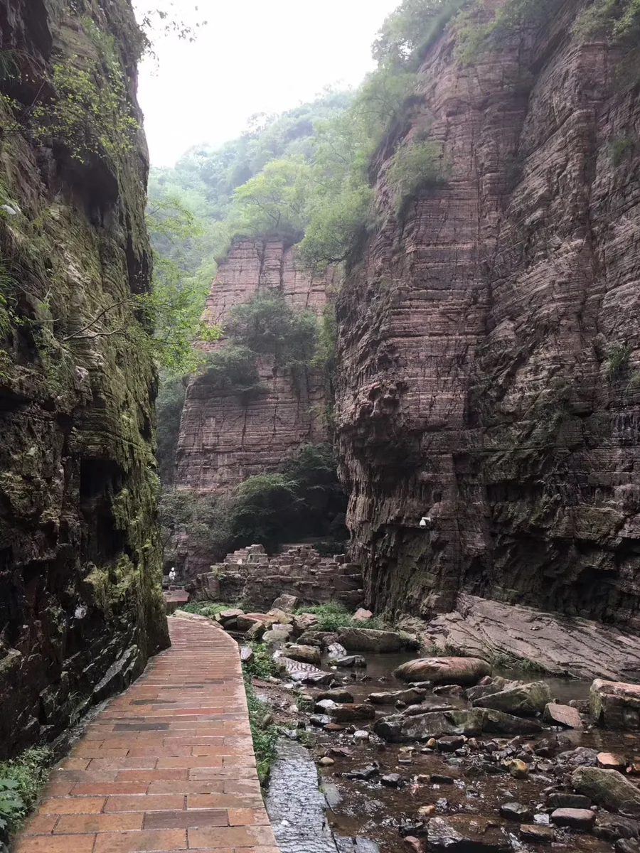 A narrow sandstone passage and streamside walkway in Longtan Grand Canyon, Henan.