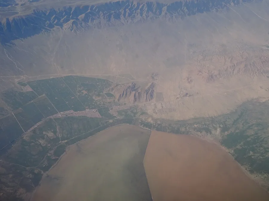 The shore of Barkol Lake and its surrounding fields and arid hills, photographed from a passenger aircraft. Photographed on 19 July 2018.