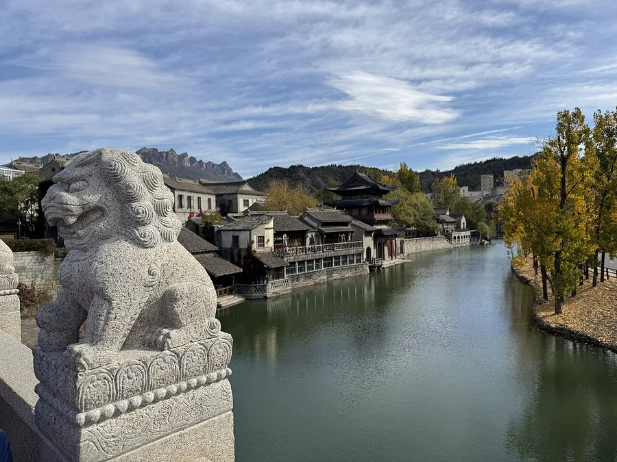 Gubei Water Town seen from its entrance bridge, with waterfront buildings and a stone lion.