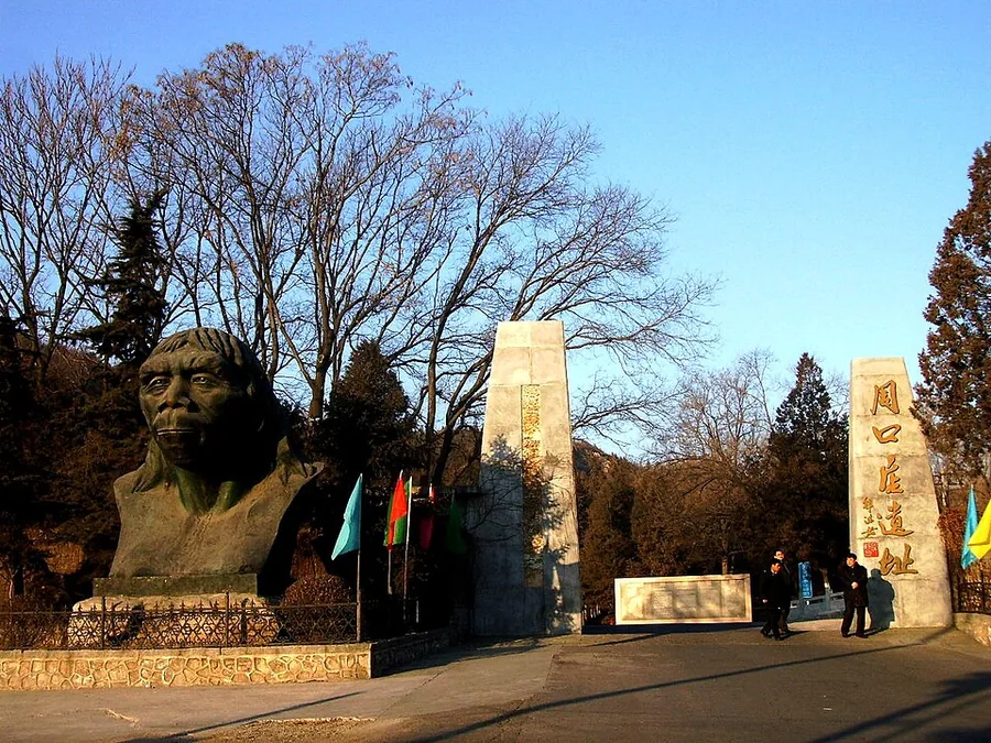 Entrance gate of the Zhoukoudian Peking Man Site with a bronze bust and stone pillars inscribed Zhoukoudian Site