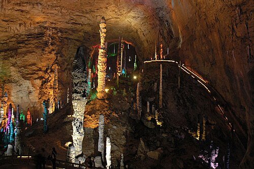 A cavern filled with tall, colourfully lit stalagmite columns