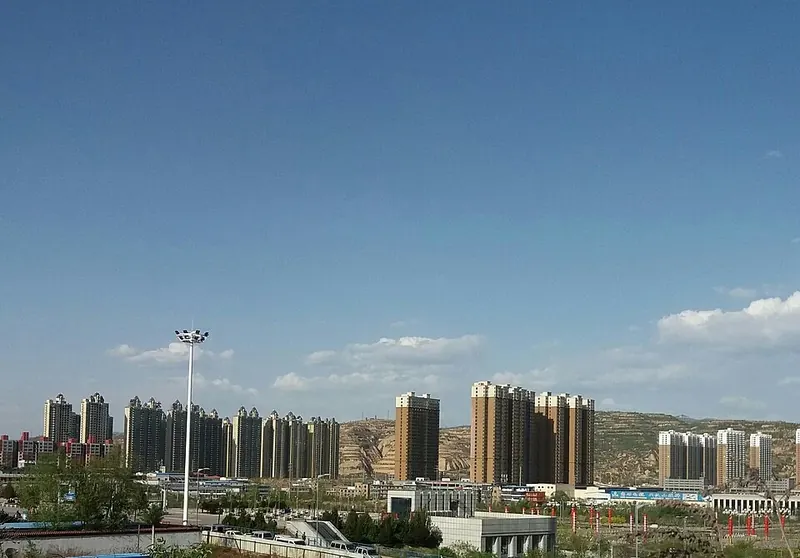 An urban skyline in Lüliang, Shanxi (山西吕梁), with nearby hills beyond.