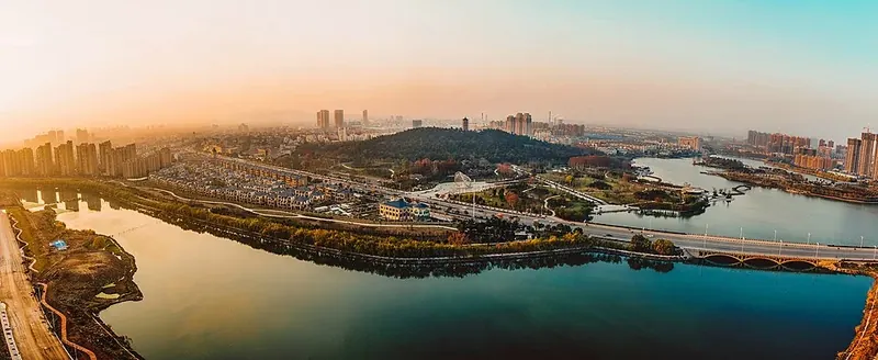 A hazy view of a lake and mountain park among apartment towers in Bengbu
