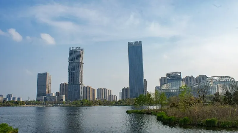 A park and lake in front of a modern city skyline in Yingzhou District, Fuyang