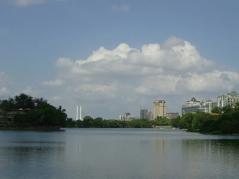 A calm lake with trees in the foreground and Huizhou's skyline in the distance