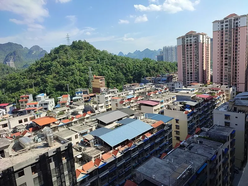 Hechi (河池) viewed from QianAn International Hotel, with urban buildings and nearby karst hills.