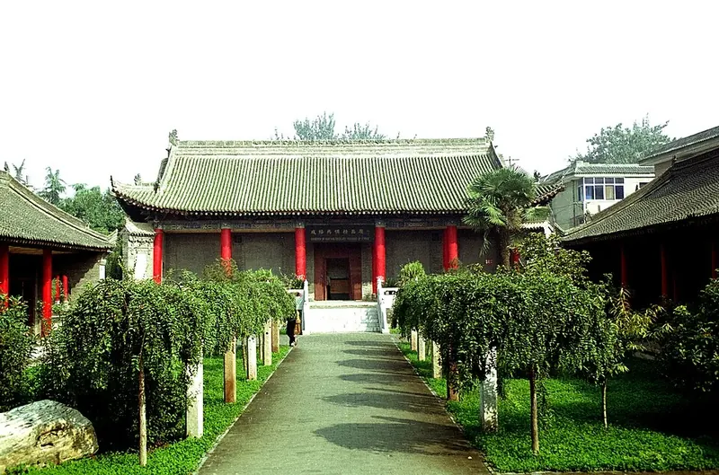 Traditional Chinese hall with red columns at the end of a tree-lined garden path at Xianyang Museum