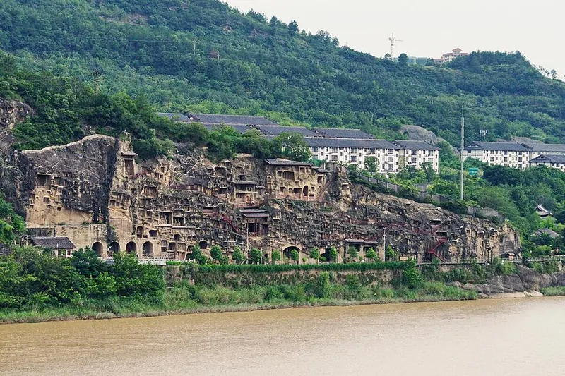 Cliff face covered in carved Buddhist niches above a river