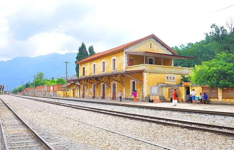 Yellow colonial-style railway station building beside the tracks