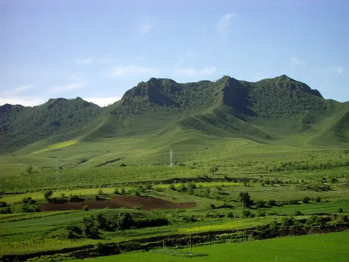 Green grassland, fields and mountain ridges in Hexigten Banner, Inner Mongolia. Capture date unverified; source date metadata conflicts with the visible season.