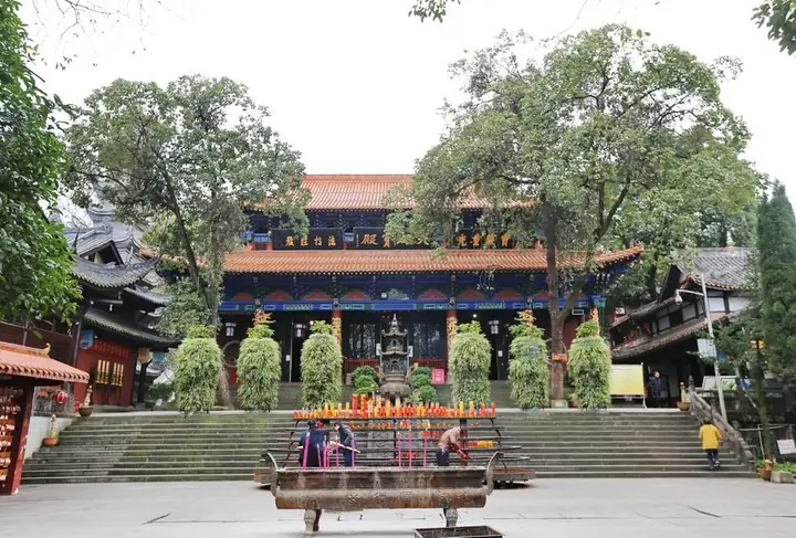 Ornate red-and-gold temple hall with an incense burner and worshippers in the foreground