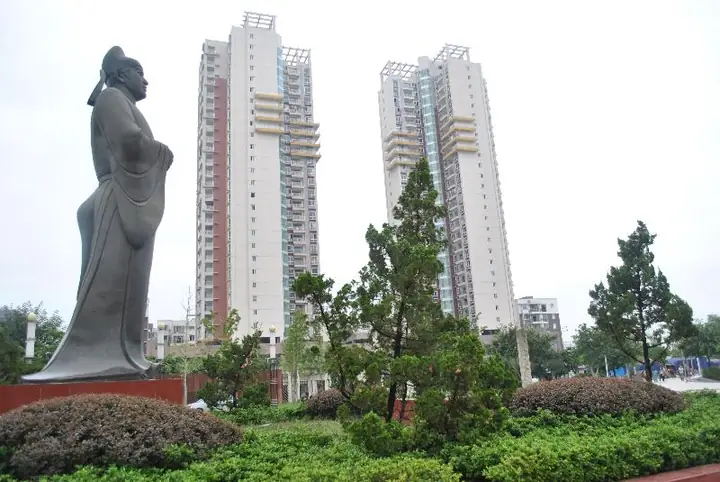 A landscaped square and nearby residential towers in Shehong.