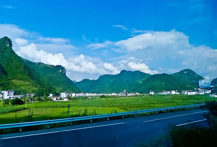 Fields, roadside buildings and wooded hills in Tongzi County.