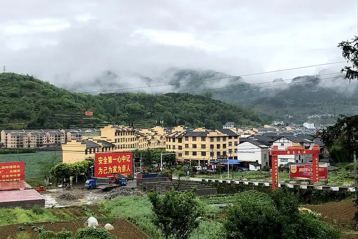 Xinzhou Town in Zheng'an County, with buildings below misty wooded hills.