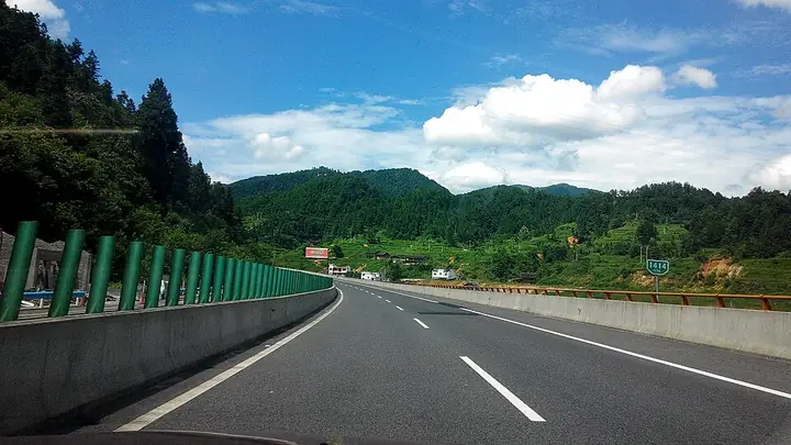 The G56 expressway through Dewang in Jiangkou County, with wooded hills beside the road.