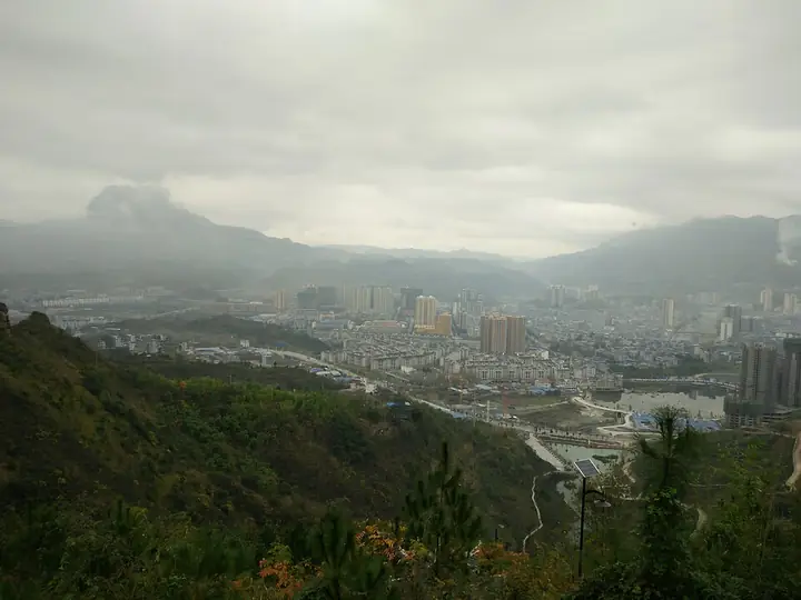 The urban area of Yinjiang Tujia and Miao Autonomous County beneath cloud-covered hills.