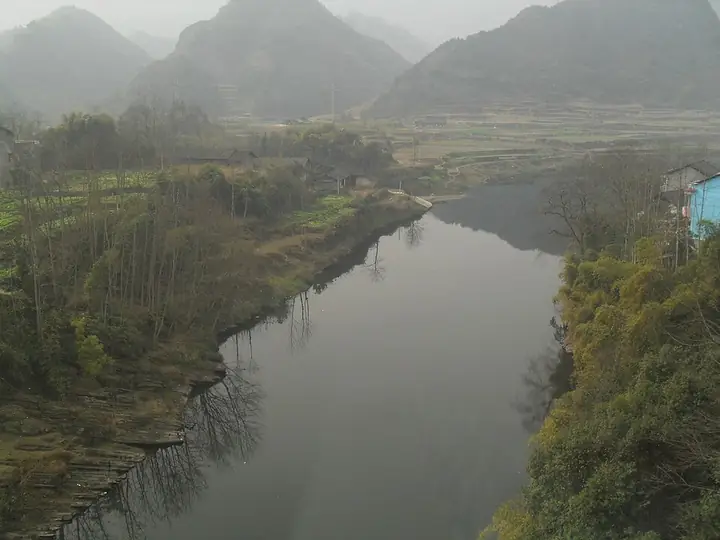 A stream, fields and folded hills in Songtao Miao Autonomous County.