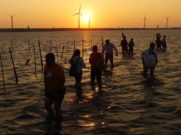 Sunset at Gaomei Wetlands, with visitors and offshore wind turbines
