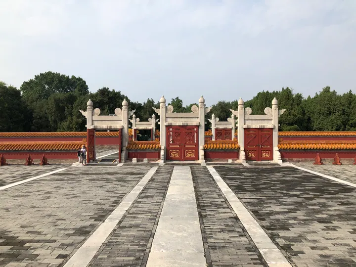 Ornate red ceremonial gate with yellow-glazed tile walls under a blue sky