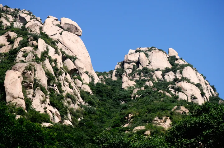 Weathered granite rock formations on a forested ridge at Fenghuangling