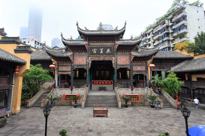 Ornate traditional Chinese gate building with red lanterns and modern towers behind