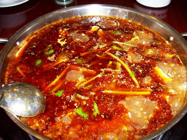 A pot of deep red Chongqing hotpot broth with a ladle