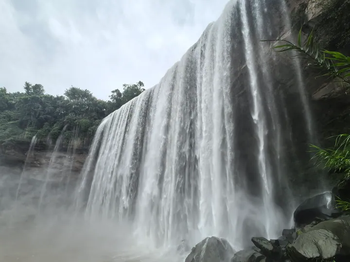 Wide waterfall cascading over a cliff into a misty pool at Wanzhou Grand Falls