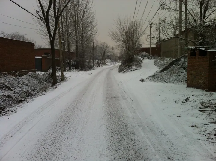 Snow-covered lane between brick courtyard walls in Kaiping District