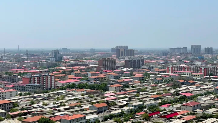City skyline of Julu County with residential rooftops under a hazy sky