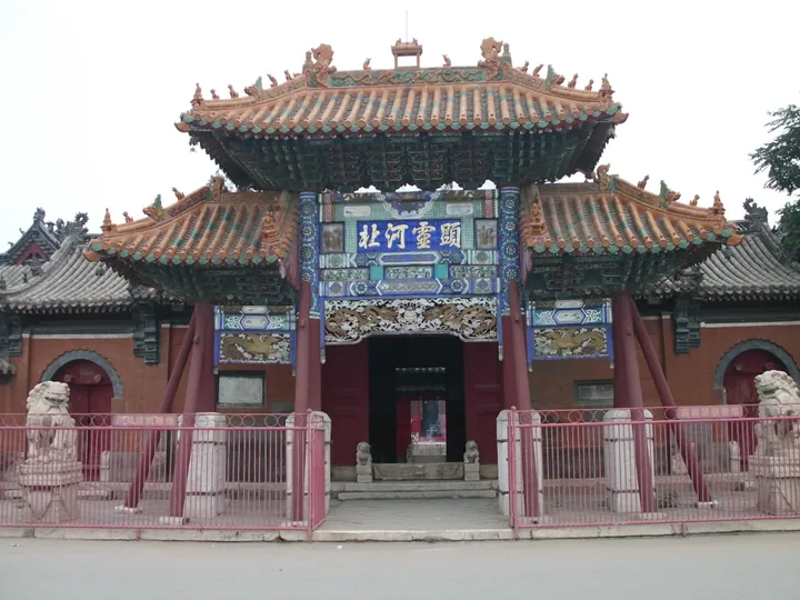 Ornate multi-tiered temple gate with stone lions and red railings in Anguo