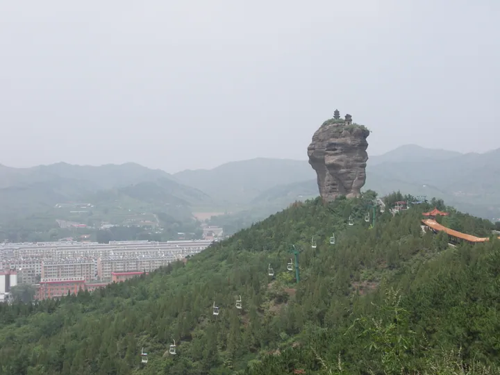A twin rock pinnacle topped with a small pagoda amid forested hills near Chengde