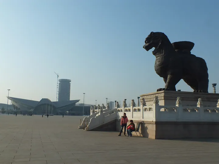 A large lion statue on a stone platform at Lion City Square, Cang County
