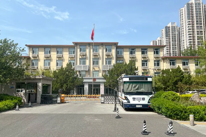 A government office building with a flagpole and parked bus in front