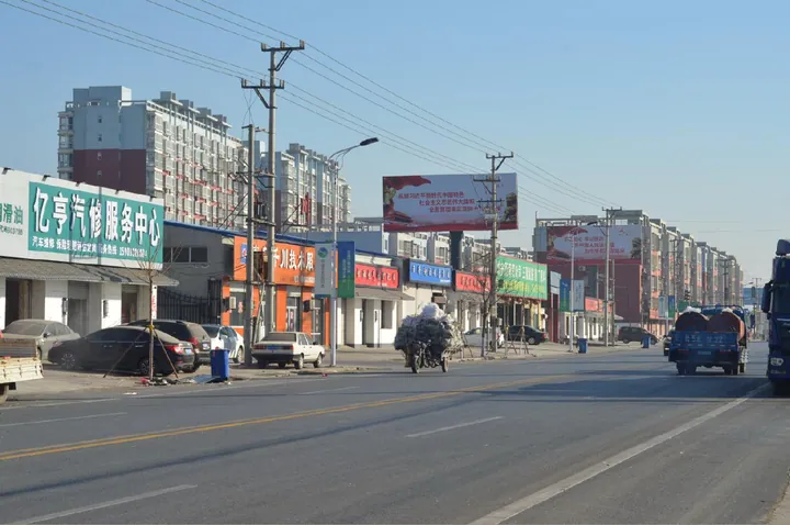 Shops and traffic along a street in Zuogezhuang Town, Wen'an County