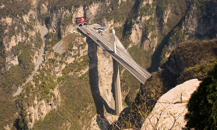 A tall cable-stayed bridge spanning a deep rocky canyon