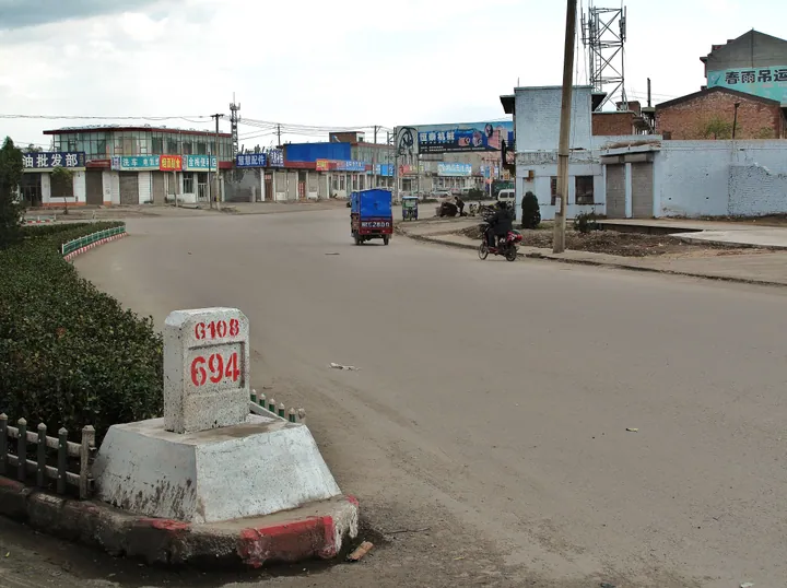 A street with shops and a highway distance marker in a town in Qi County, Shanxi