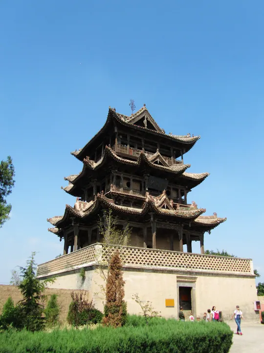 A tall multi-tiered wooden pagoda-like tower under a clear blue sky
