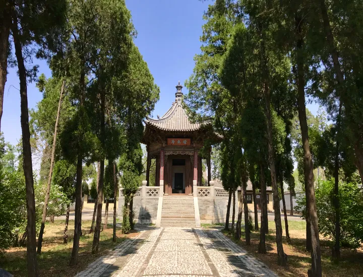 A traditional Chinese pavilion at the end of a tree-lined path