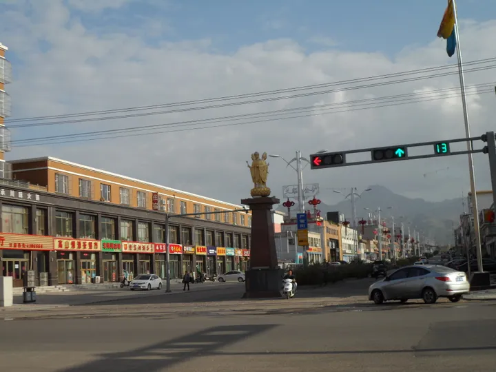 Town street with a statue, shops and mountains in the background in Fanshi County