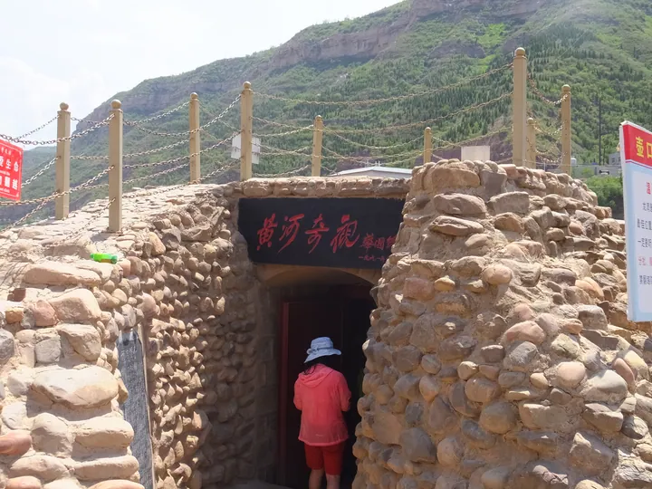 A stone-built tunnel entrance labelled 'Yellow River Wonder', leading into Dragon Cave, Ji County
