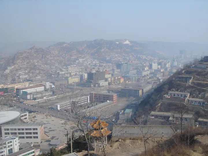 A hazy elevated townscape of Xiangning County with hills in the background