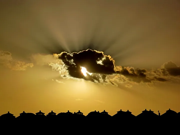Silhouette of Mongolian yurts under a glowing sunset sky
