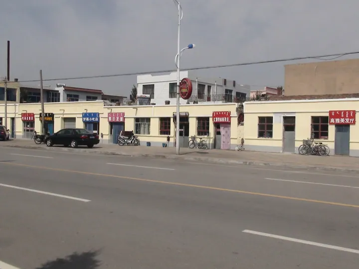 A street with shops, bicycles and cars in Wulan Town, Otog Banner