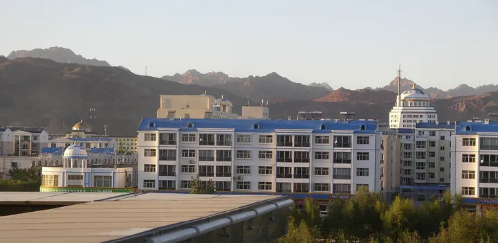 Blue-roofed modern buildings with a mountain backdrop in Urad Rear Banner